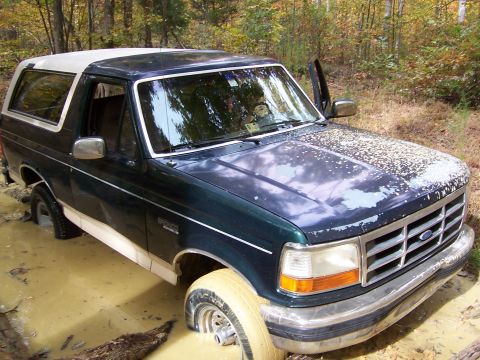 1992 Ford Bronco - A 1992 Ford Bronco is stuck in a muddy off-road trail with its tires deep in the mire.