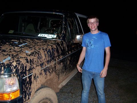 1992 Ford Bronco - A man poses next to a heavily mud-splattered SUV after an off-road excursion.