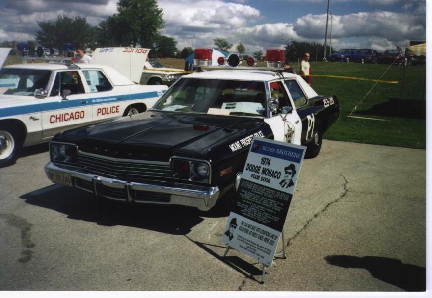 Black and white 1974 Dodge Monaco police car with "Blues Brothers" sign