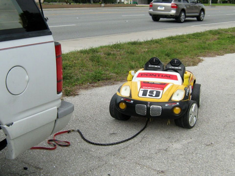 Yellow toy car with 'Pontiac' and '19' on it being towed by a larger vehicle