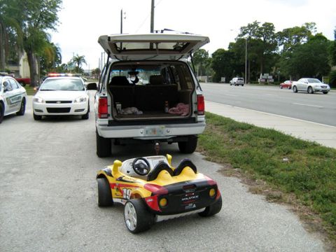 1999 Ford Ranger - A toy car and an SUV are parked on the side of the road, with police cars in the background.