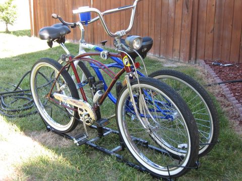 1994 Ford Bronco - Two cruiser bicycles are parked on a rack in a grassy yard next to a wooden fence.