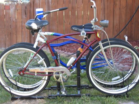 1994 Ford Bronco - Two cruiser bicycles are parked side-by-side in front of a wooden fence, with one slightly behind the other.