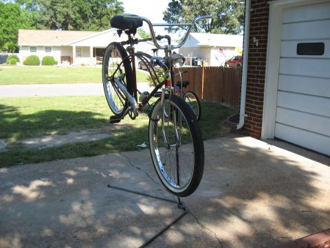 1994 Ford Bronco - A bicycle is propped up on a stand in a driveway, with a house and garage visible.
