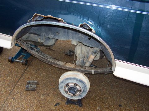 1992 Ford Bronco - Vehicle's rear wheel well shows significant rust and damage, with suspension components exposed.