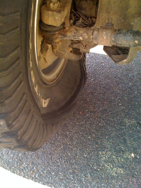 1992 Ford Bronco - A vehicle's tire is flat, showing the suspension components and the road surface.