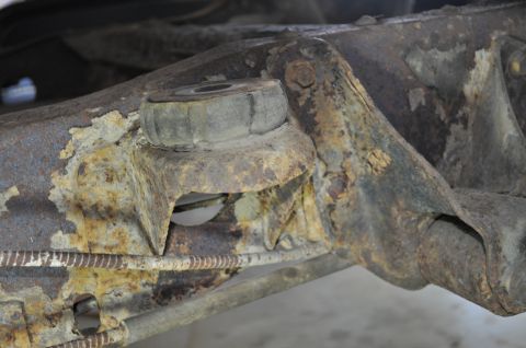 1986 Ford Bronco - Close-up view of a heavily rusted suspension component, likely from a vehicle's undercarriage.