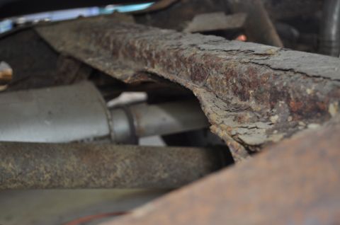 1986 Ford Bronco - Close-up view of heavily rusted vehicle frame and exhaust system components.
