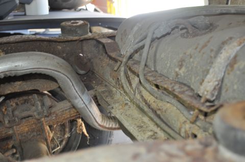1986 Ford Bronco - Undercarriage view of a vehicle, focusing on the fuel tank and exhaust system, with visible rust and wear.
