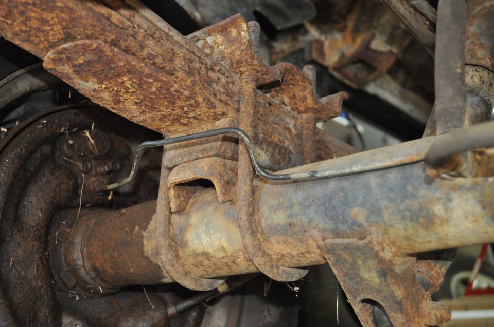 Close-up of rusty rear axle and leaf spring assembly on a vehicle