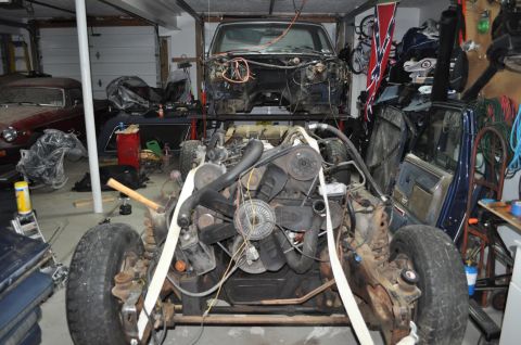 1986 Ford Bronco - 1986 Ford Bronco undergoing teardown in a garage, engine and chassis separated from the body.