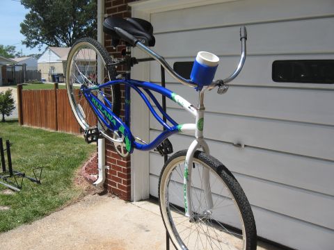 1994 Ford Bronco - A blue and white beach cruiser bicycle is mounted on a rack in front of a garage door.
