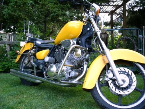 1976 Yamaha Virago - Yellow motorcycle with chrome accents parked outdoors on a grassy lawn.