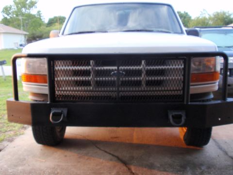 1995 Ford Bronco - The front view of a 1995 Ford Bronco shows its heavy-duty bumper and grille, with a second vehicle visible in the background.
