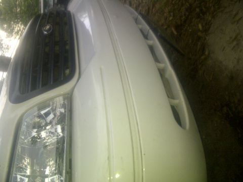 2000 Ford Crown Victoria - Close-up of the front corner of a white sedan, focusing on the headlight and grille details.