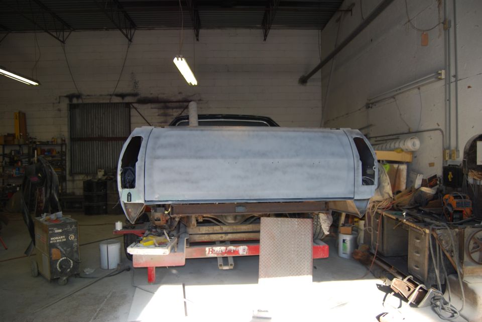 Gray truck bed with a camper shell, viewed from the rear, in a workshop