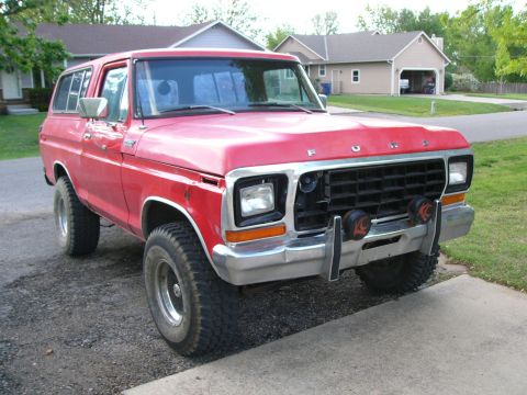 1979 Ford Bronco - This red Ford Bronco is parked in front of a suburban house and garage.