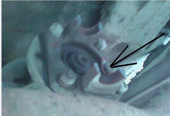 close-up of a vehicle suspension component with an arrow pointing to a worn area