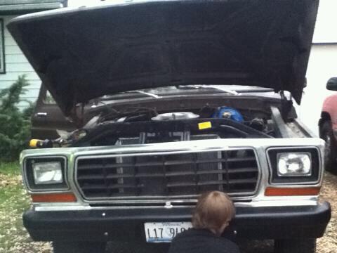 1979 Ford Bronco - A child inspects the engine of a 1979 Ford Bronco with its hood raised.