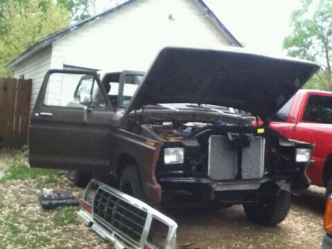 1979 Ford Bronco - This 1979 Ford Bronco is shown with its hood open, revealing the engine bay and a detached grille in the foreground.