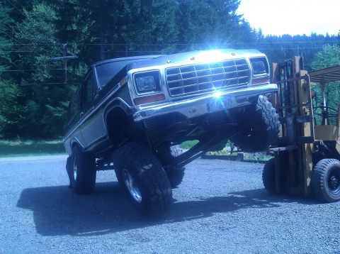 1979 Ford Bronco - Forklift lifting a lifted 1978 Ford Bronco.