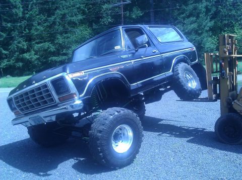 1979 Ford Bronco - This heavily modified Ford Bronco is being lifted by a forklift, showing off its suspension and large tires.