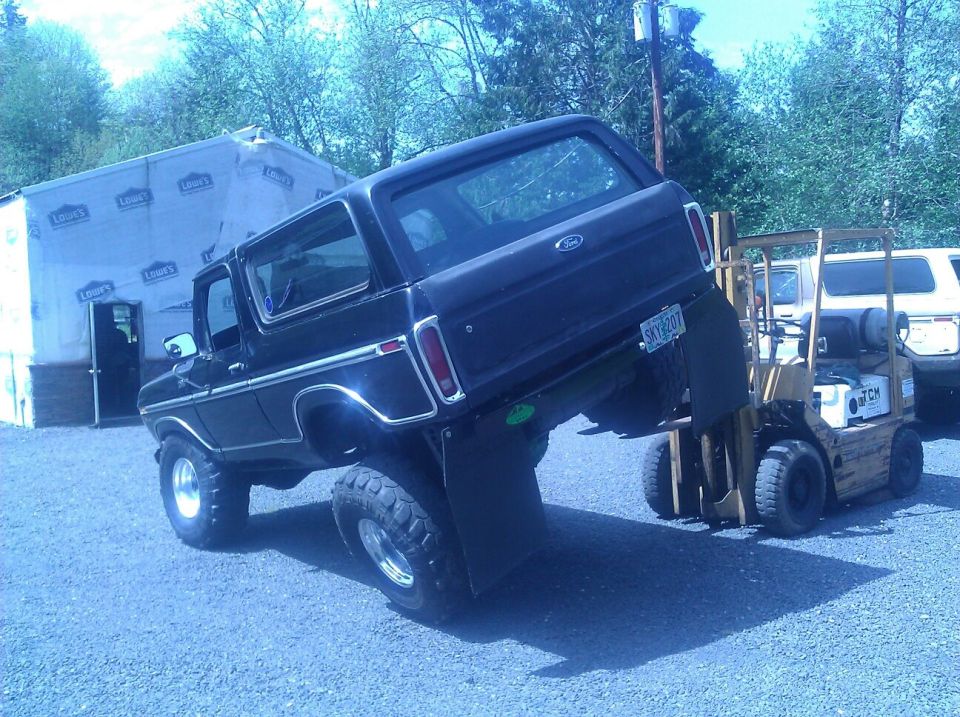 Black 1979 Ford Bronco lifted by forklift, rear view