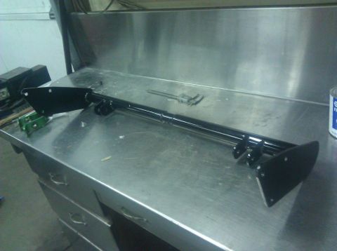 1979 Ford Bronco - A black metal component, possibly a suspension part, rests on a stainless steel surface.