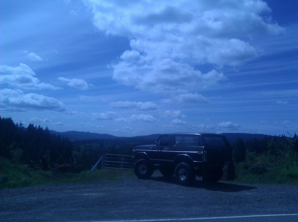 Black 1978 Ford Bronco parked on a gravel lot with a scenic mountain view