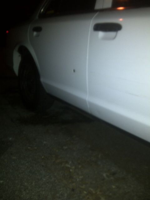2000 Ford Crown Victoria - Side view of a white sedan, showing the door and a small dent near the rear wheel well.