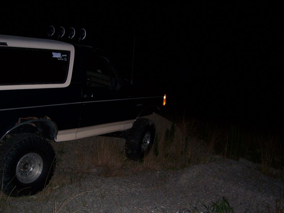 Side view of a 1992 Ford Bronco at night, parked on gravel with some grass