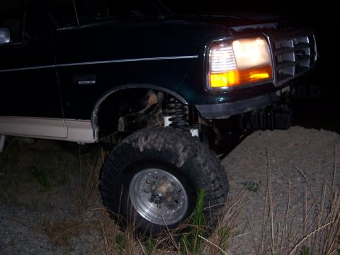 1992 Ford Bronco - A dark green 1992 Ford Bronco is shown with a lifted suspension and off-road tires, indicating its off-roading capabilities.