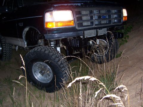 1992 Ford Bronco - This lifted Ford Bronco is navigating rough terrain at night.