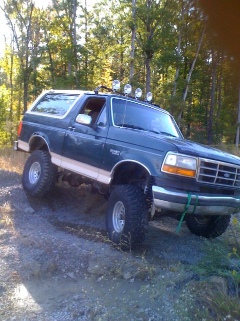 1992 Ford Bronco - This 1992 Ford Bronco is navigating a rough, wooded terrain with its off-road modifications.