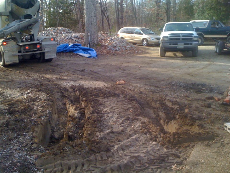 Cement truck, minivan, and pickup truck at a muddy construction site