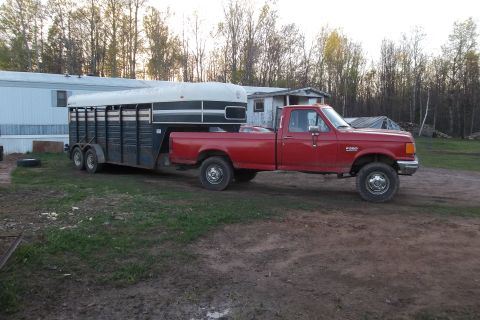 1987 Ford F-250 - A red 1987 Ford F-250 pickup truck is hitched to a trailer in a rural setting.
