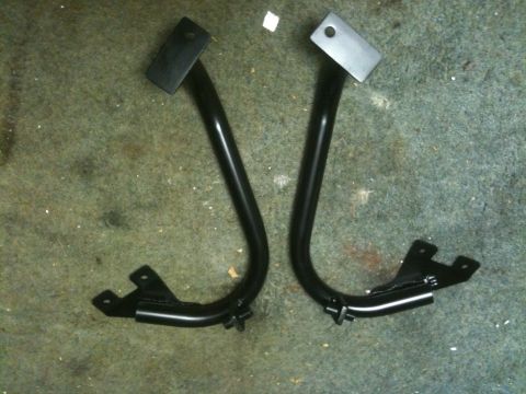 1995 Ford Bronco - Two black metal brackets, likely for a vehicle modification, are shown on a carpeted surface.