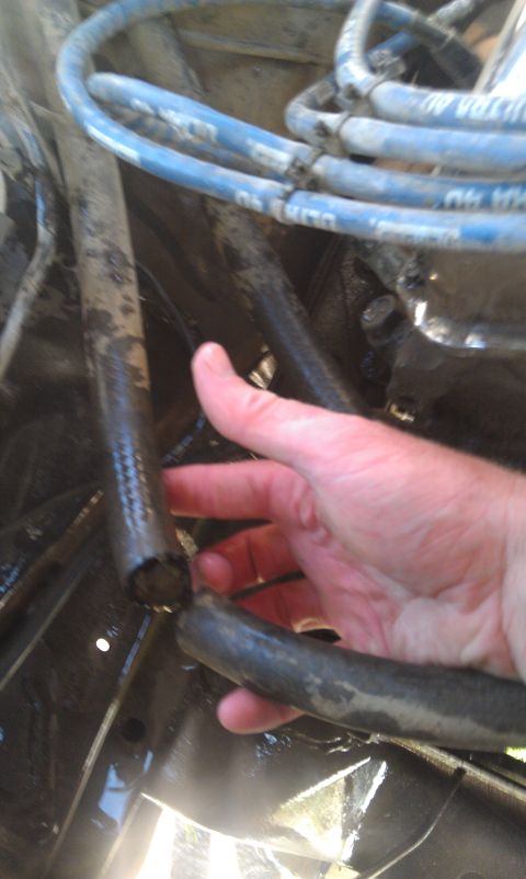 1978 Ford Bronco - A hand is shown inspecting a damaged hose in the engine compartment, with blue spark plug wires visible.