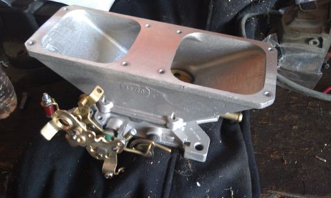 1978 Ford Bronco - Close-up of a dual-throat carburetor intake manifold, showing mechanical linkage and casting marks.