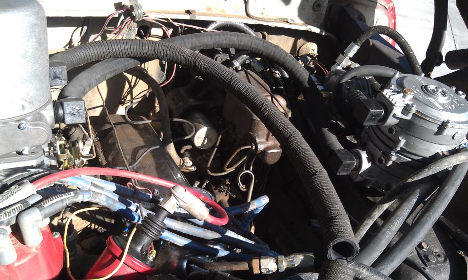 Engine bay with hoses, wires, and alternator. Some text visible on spark plug wires