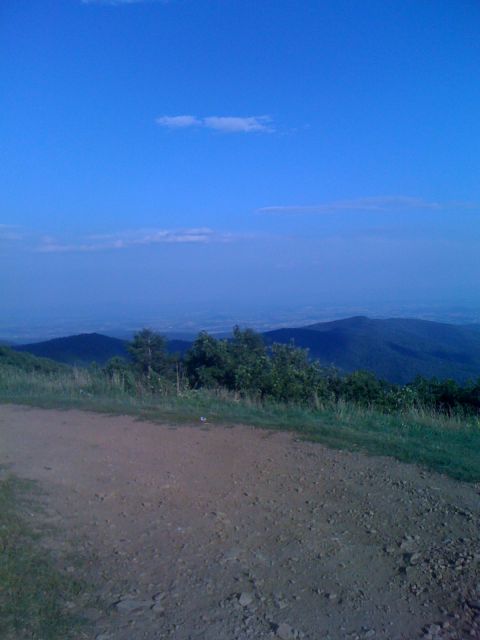 1992 Ford Bronco - A scenic view of mountains under a clear blue sky, with a dirt road in the foreground.