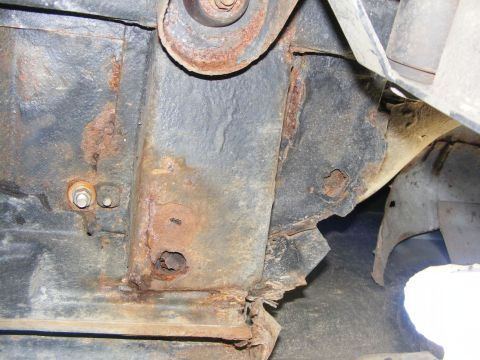 1978 Ford Bronco - Close-up view of a heavily rusted vehicle frame, showing significant corrosion and structural damage.