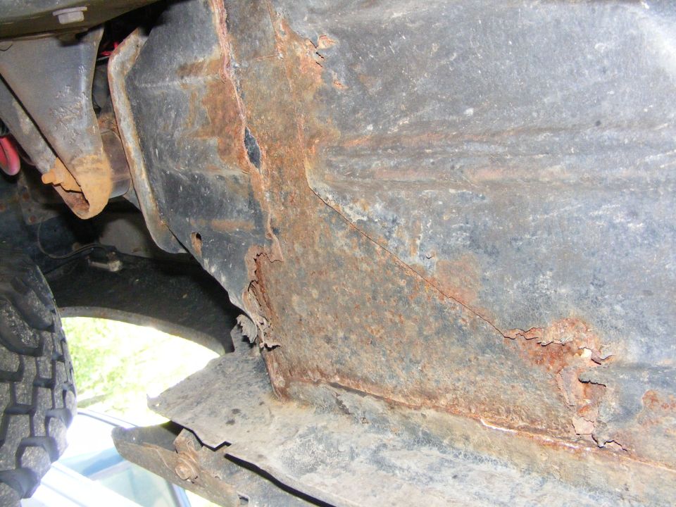 Rusted frame rail with visible damage and corrosion