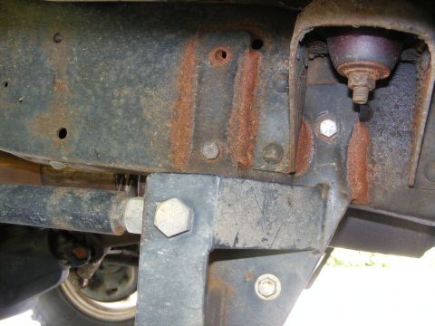 1978 Ford Bronco - The underside of a vehicle shows significant rust on its frame and suspension components.