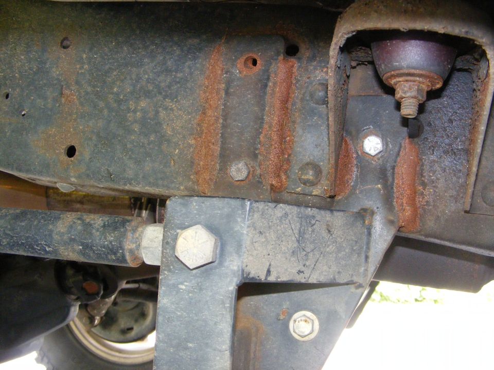 Close-up of rusted vehicle frame with bolts and suspension parts visible