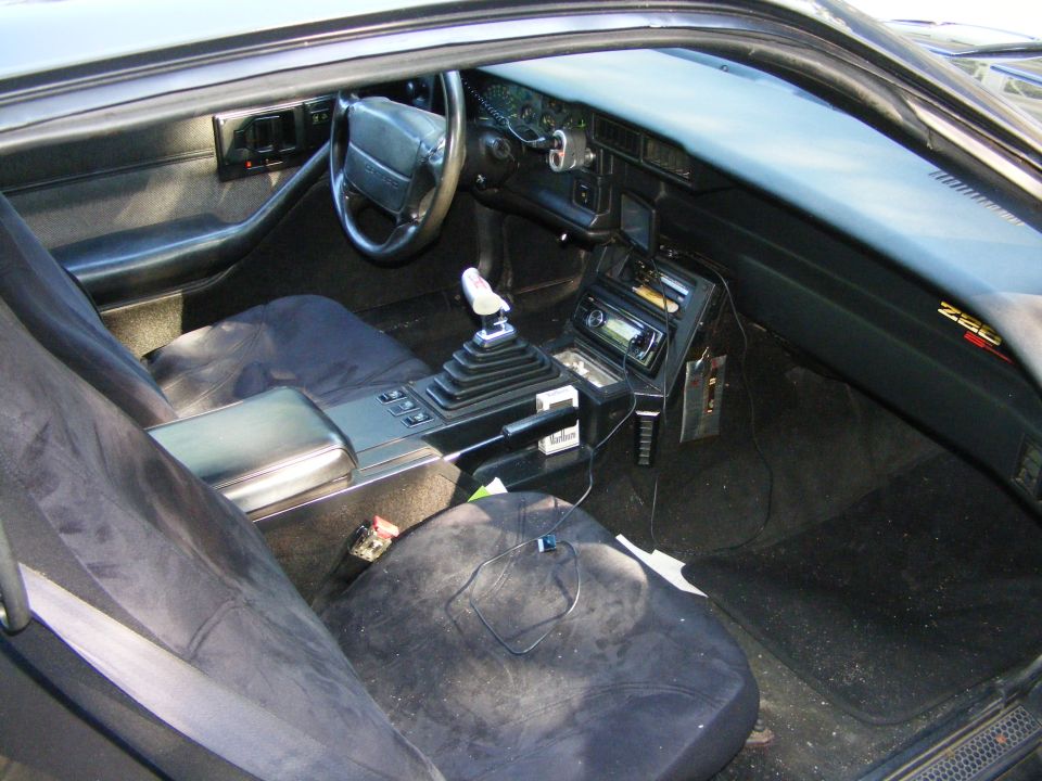 Interior view of a Z28 Camaro showing the dashboard, steering wheel, center console with manual shifter, and seats