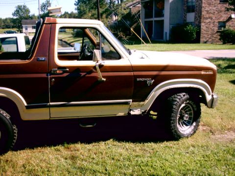 1980 Ford Bronco - The side profile of a brown and white 1980 Ford Bronco shows its distinctive body style and badging.