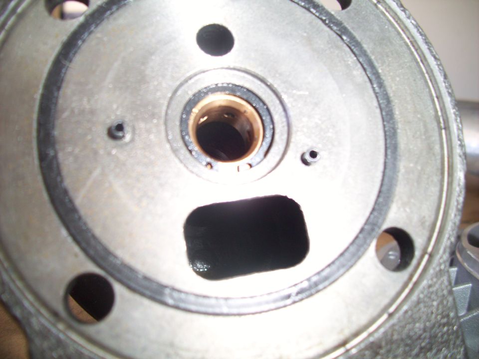 Close-up of a metal automotive part with a circular gasket, a central bearing, and a rectangular cutout