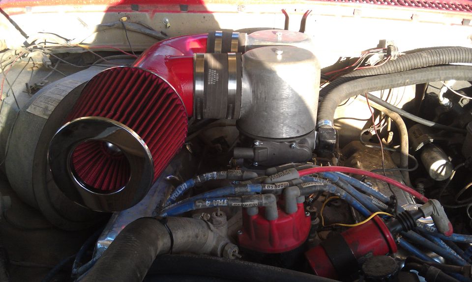 Engine bay with red cone air filter, silver air intake housing, and blue spark plug wires