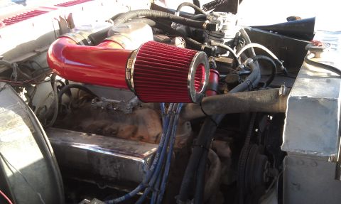 1978 Ford Bronco - Close-up view of an engine bay a red aftermarket air intake system and chrome valve covers.